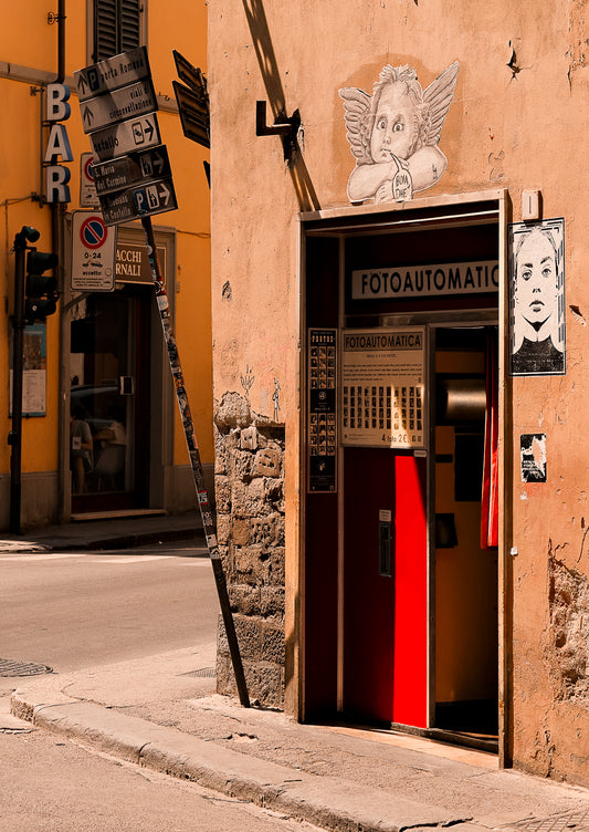 Vintage photo booth on a street corner with street signs and a yellow building in the background.