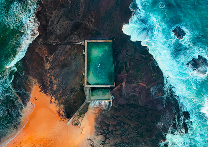 A natural pool carved into a rocky cliffside surrounded by ocean waves.