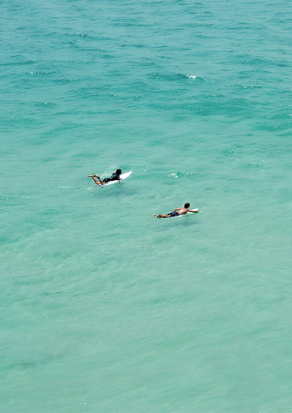 Two people surfing in clear blue water