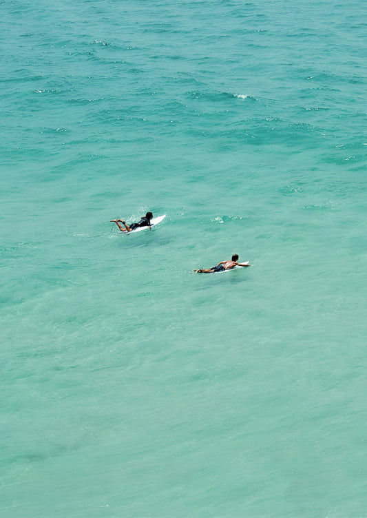 Two people surfing in clear blue water